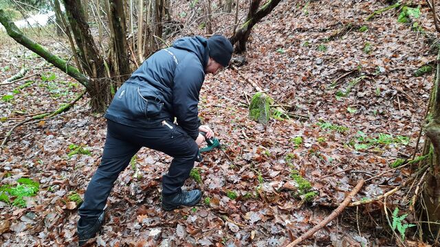 Policejní kynolog před hledáním vyvrtává otvory do země, aby se uvolnily případné pachy. Foto: David Horák 